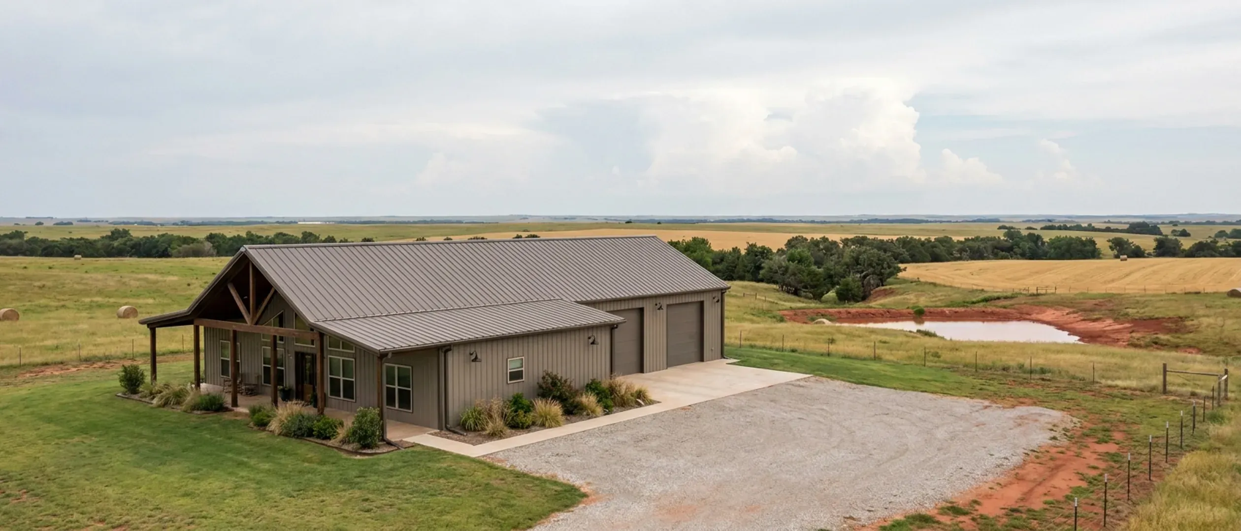 A completed barndominium with a covered entry porch and an attached shop bay, photographed in flat overcast daylight.