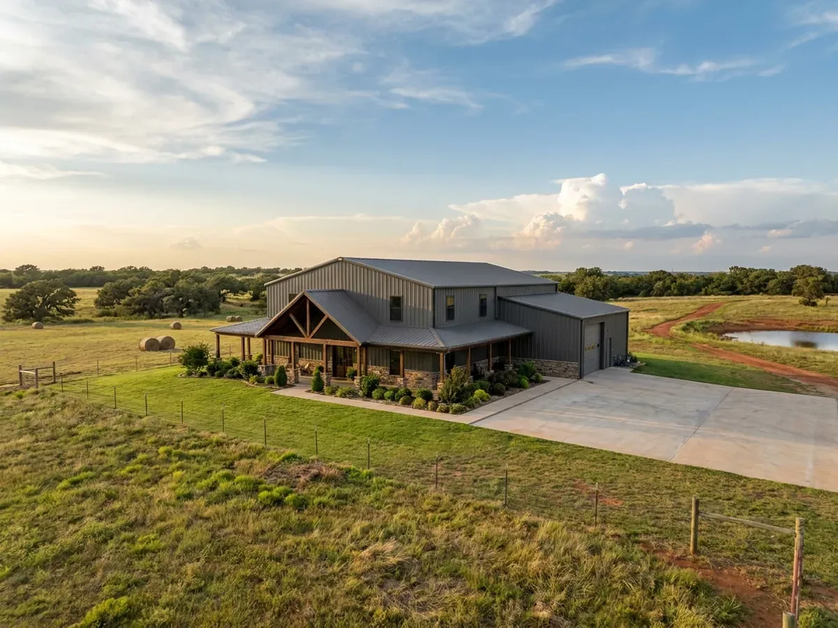 A completed barndominium home viewed from the front corner, with finished landscaping, a covered entry porch and an attached shop bay.